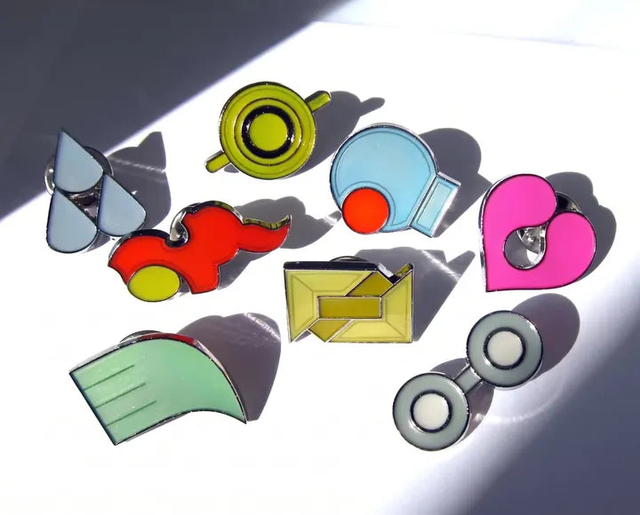 Loose Hoenn badges catching direct sunlight on a white surface