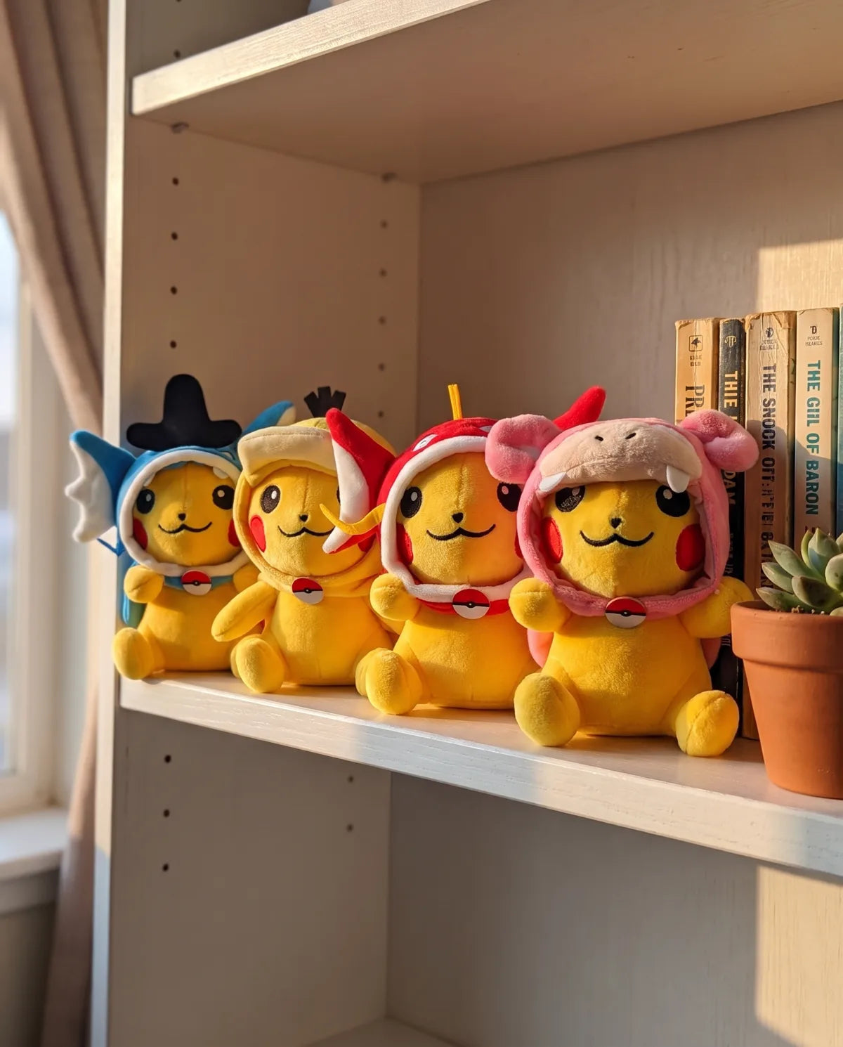 The four Little Swimmers plush sitting in a row on a bookshelf