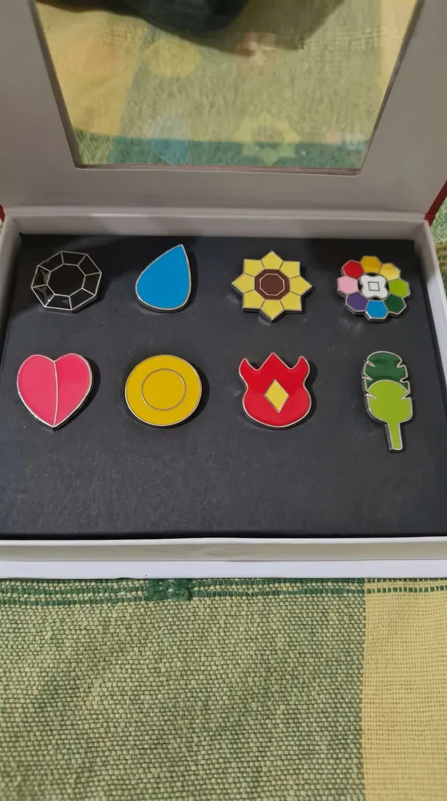 An open Kanto gift box held up, eight badges in black foam